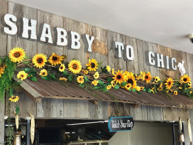 Shabby To Chic antique store sign in Coffeyville, KS featuring sunflowers and rustic wooden decor.